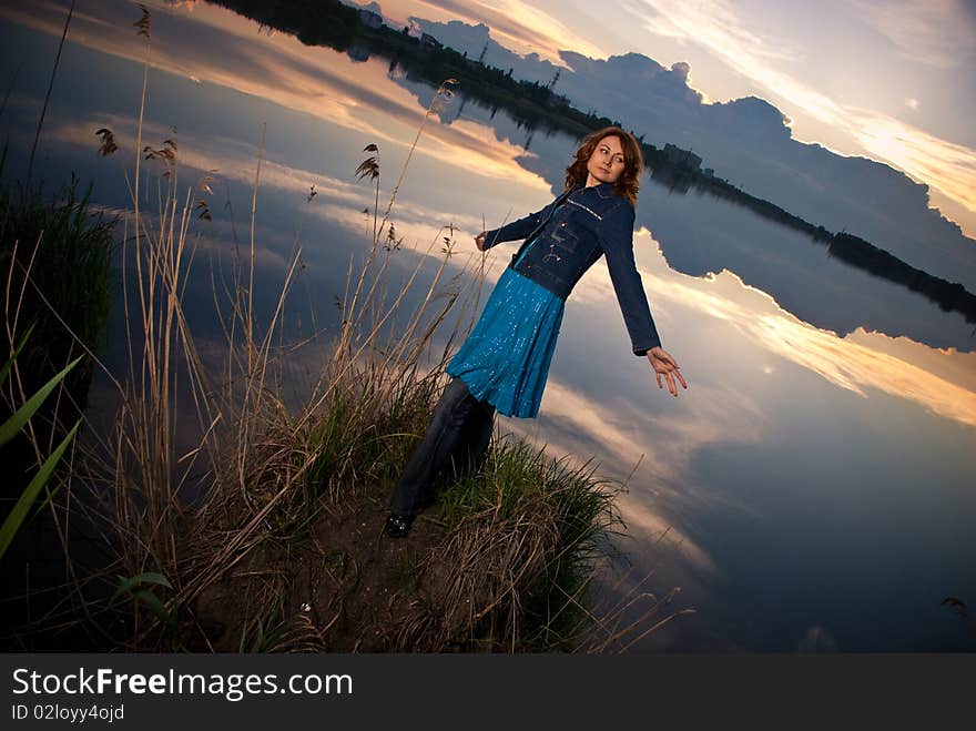 Young woman spreading arms at sunset lake. Young woman spreading arms at sunset lake