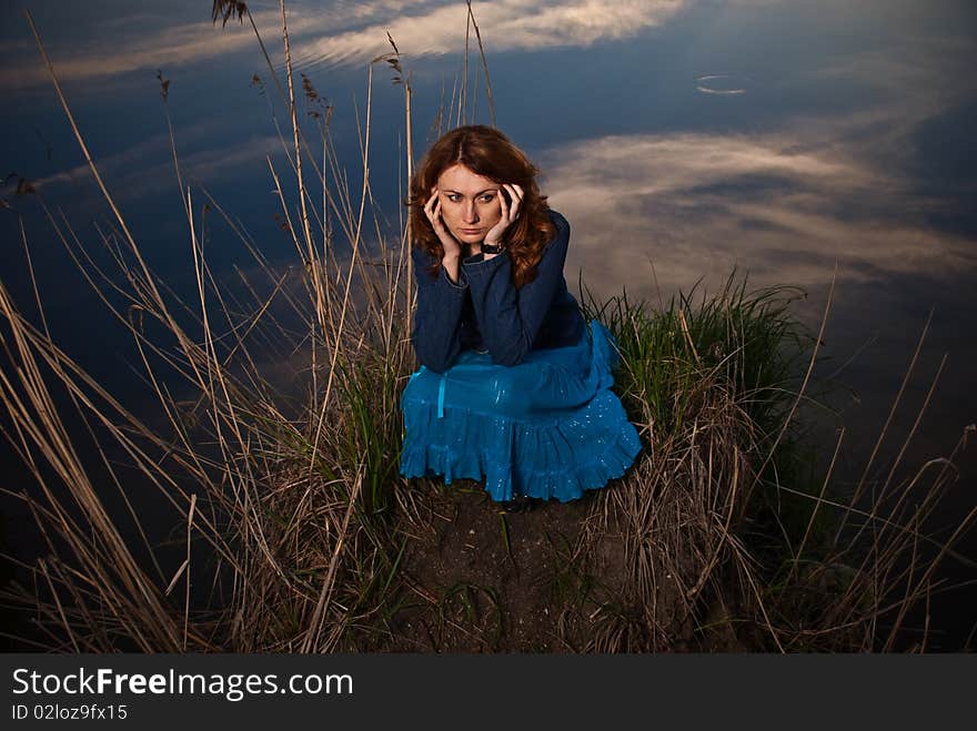 Lonely young woman at sunset lake. Lonely young woman at sunset lake