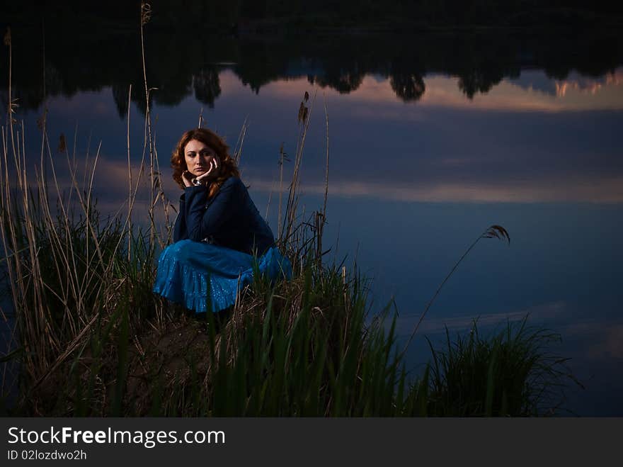 Lonely young woman at sunset lake. Lonely young woman at sunset lake