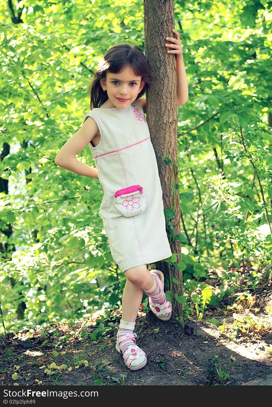 Little girl standing near a tree