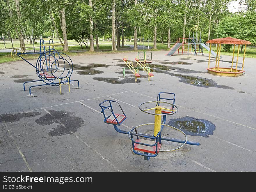 Rusty playground for the children in the middle of the green park. Rusty playground for the children in the middle of the green park.