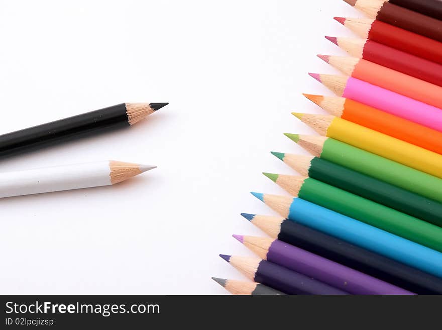 Wooden pencils of different colour on a white paper.