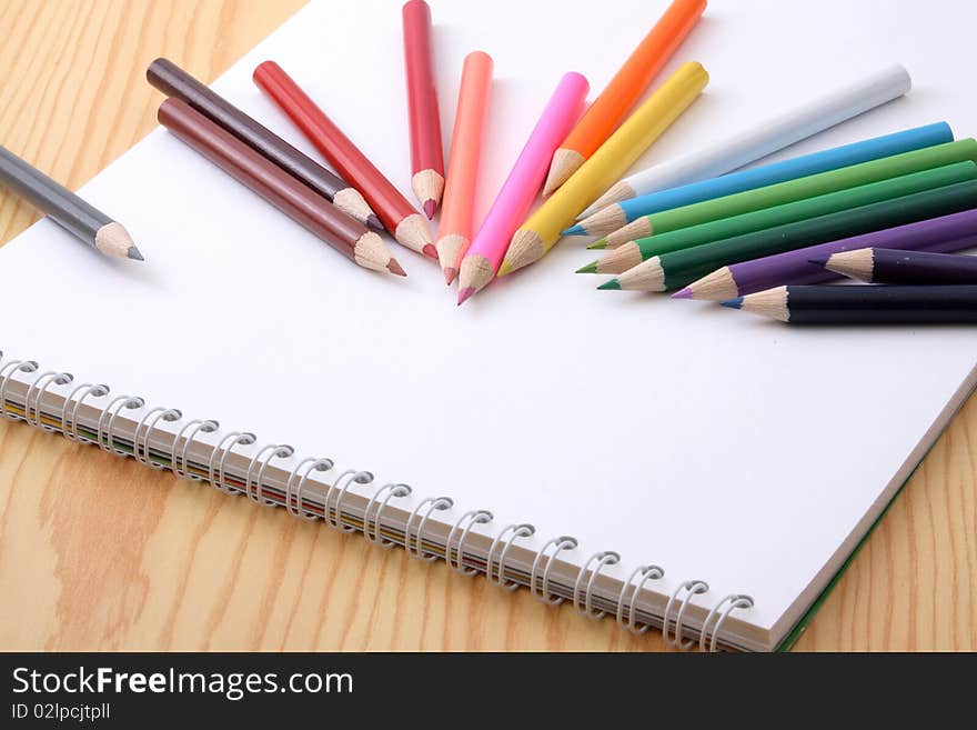 Wooden pencils of different colour on a white paper.