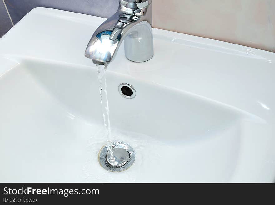 White washstand with flowing clean transparent water. White washstand with flowing clean transparent water