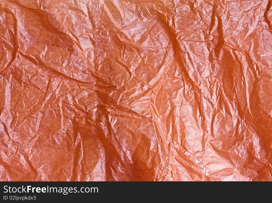 A closeup picture of scrunched up shiny orange tissue paper