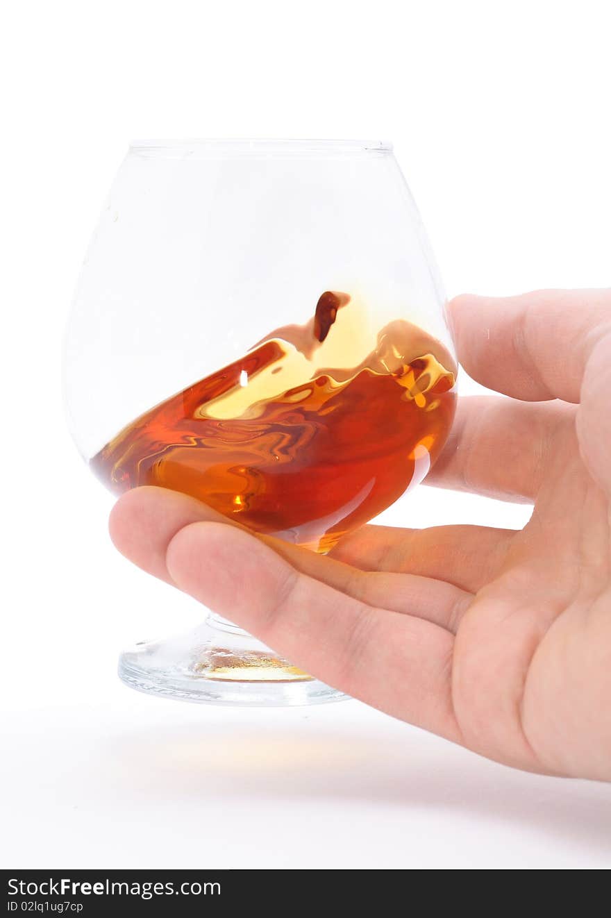 Glass of brandy holding by hand isolated on white