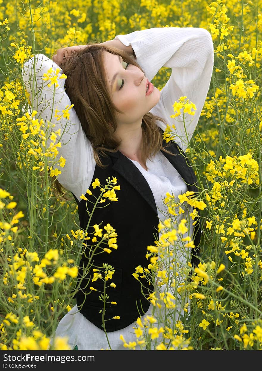 Young girl resting in rape field. Young girl resting in rape field