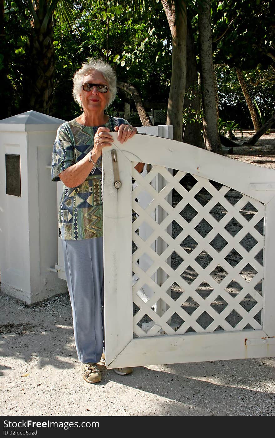 Senior Woman Standing by Open White Gate