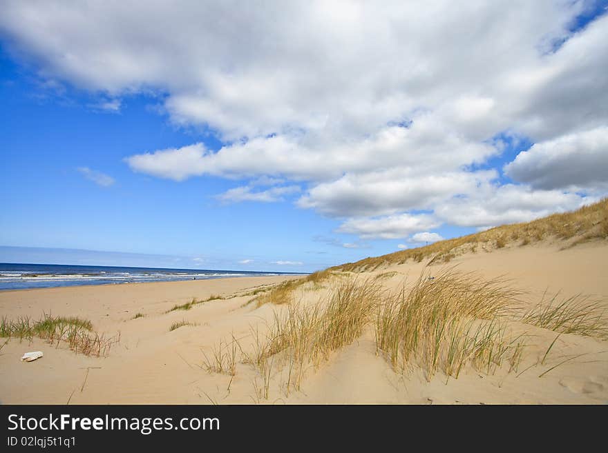 Sand dunes near to the sea with cloudy sky