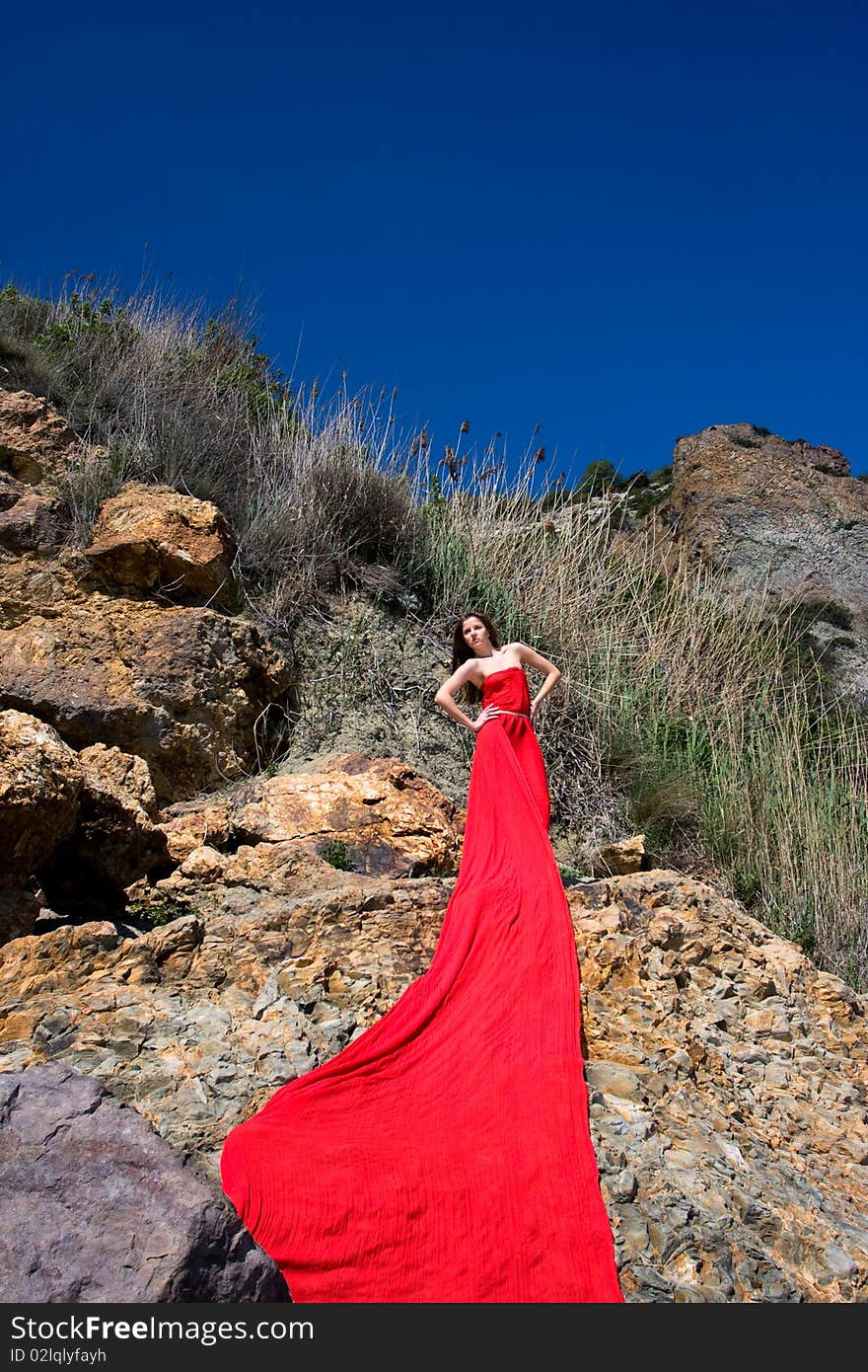 Woman in red dress from material and rocks