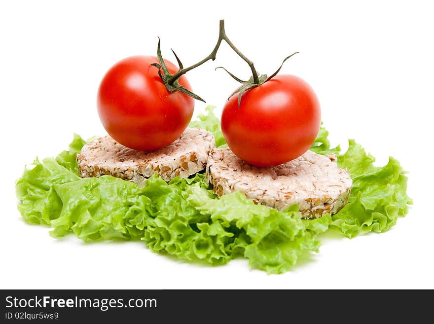 Two ripe tomatoes and small loaf of bread on sheet of the salad