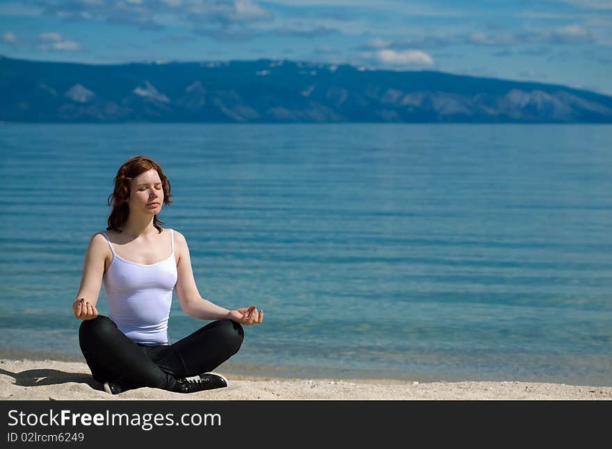 Beautiful girl meditating on the background of mountains on the lake Baikal