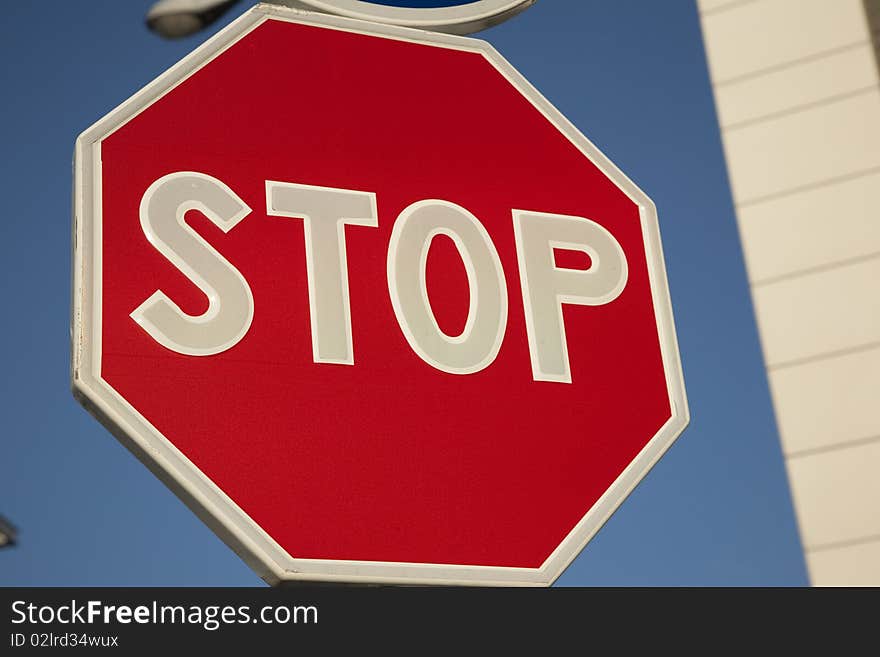 Closeup of red traffic stop sign against clear blue sky background in urban setting. Closeup of red traffic stop sign against clear blue sky background in urban setting