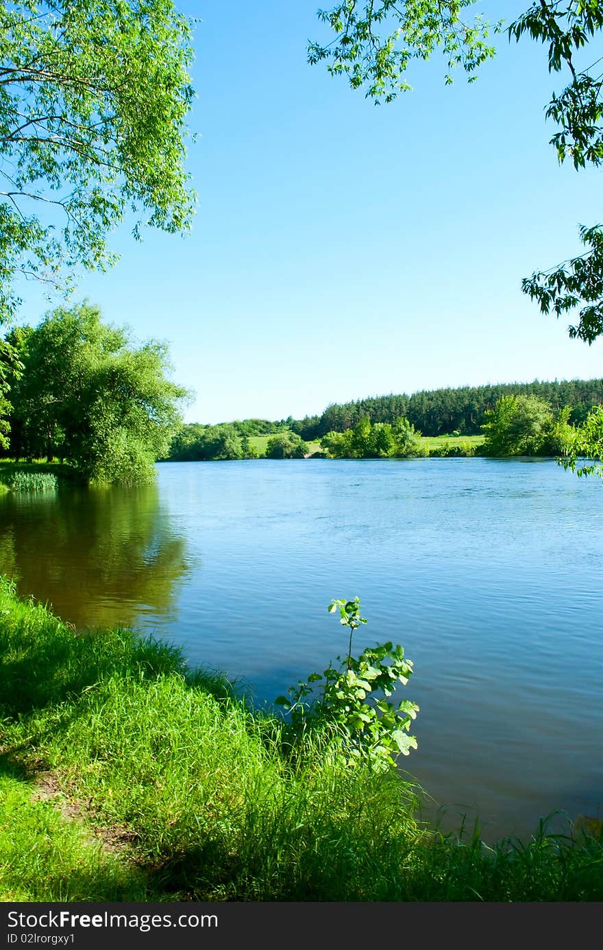 Shows the river, trees, grass and sky.