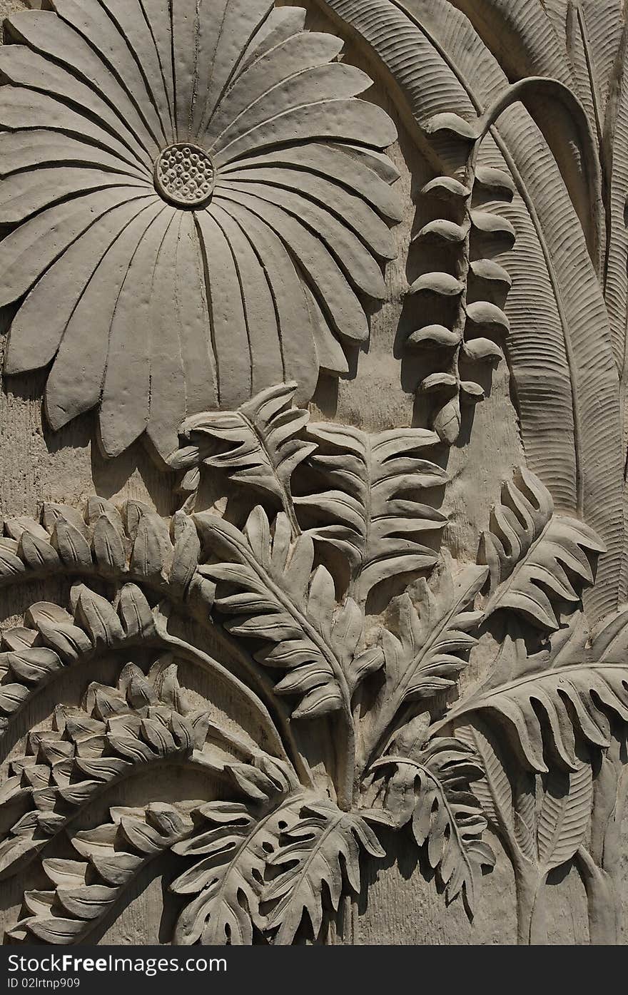 Artistic plant emboss sculpture made of concrete place on vertical wall