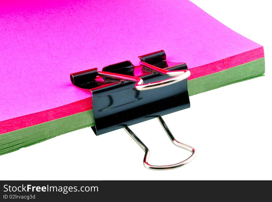 Black clamp  holds a stack of documents colored sheets