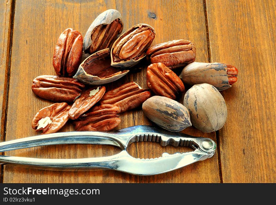 Pecans, whole and broken and Nutcracker lie on the background of a wooden table