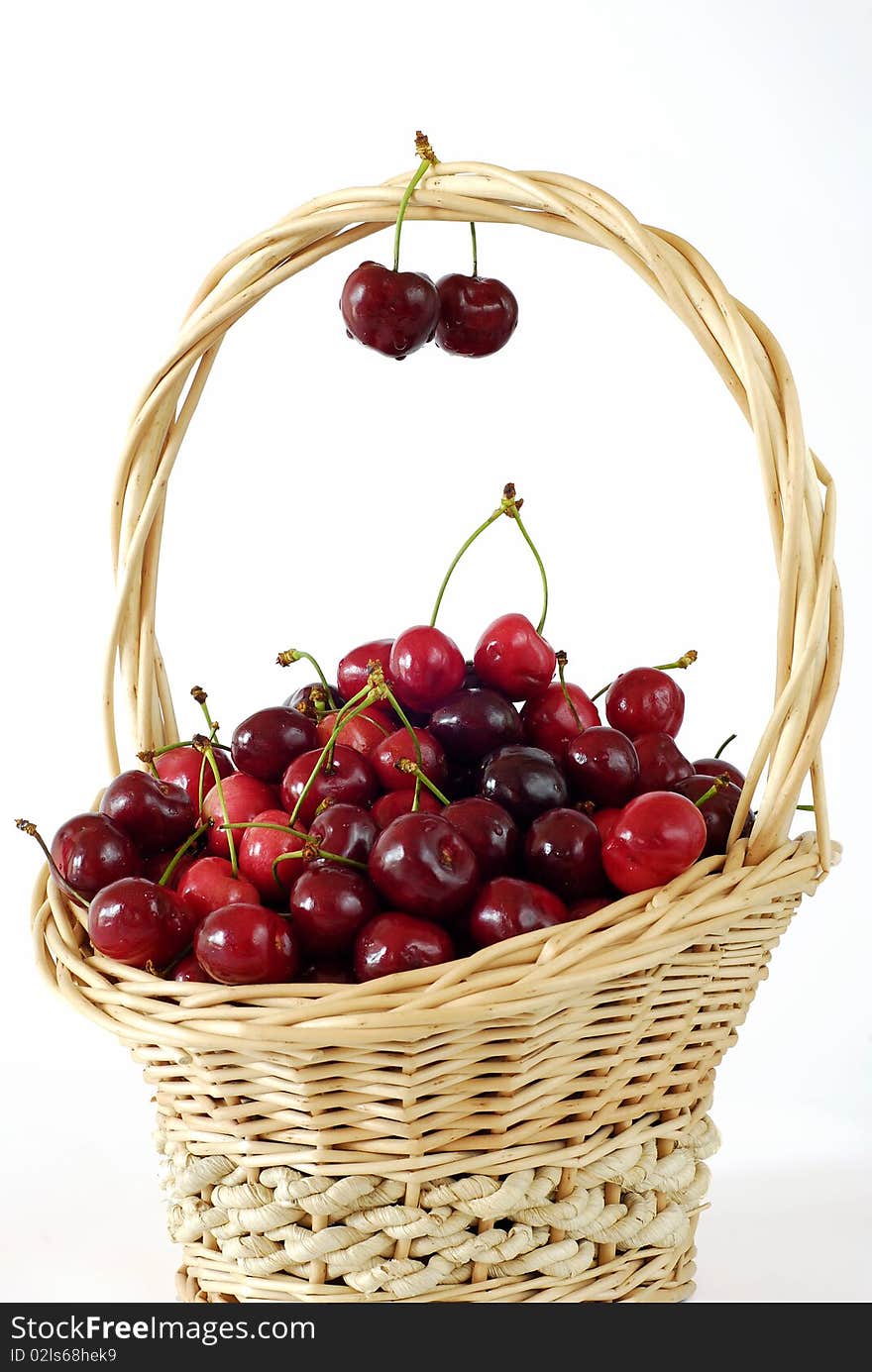 Wicker basket with fresh red cherries on the white background. Wicker basket with fresh red cherries on the white background