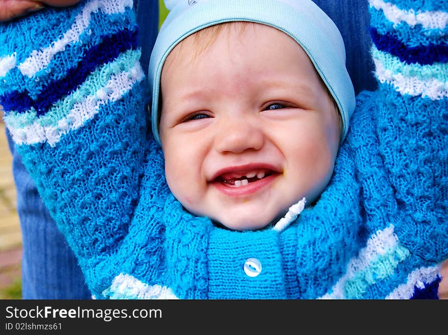 The happy little boy in a dark blue jacket laughs having lifted hands upwards. The happy little boy in a dark blue jacket laughs having lifted hands upwards