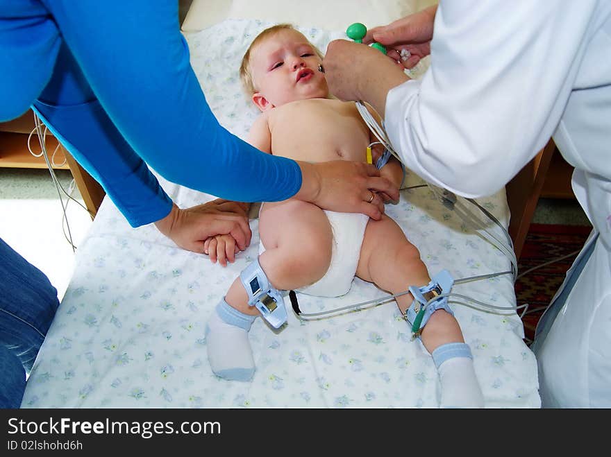 The little boy with tear-stained eyes lays on a couch in hospital and to it do the heart cardiogramme. The little boy with tear-stained eyes lays on a couch in hospital and to it do the heart cardiogramme