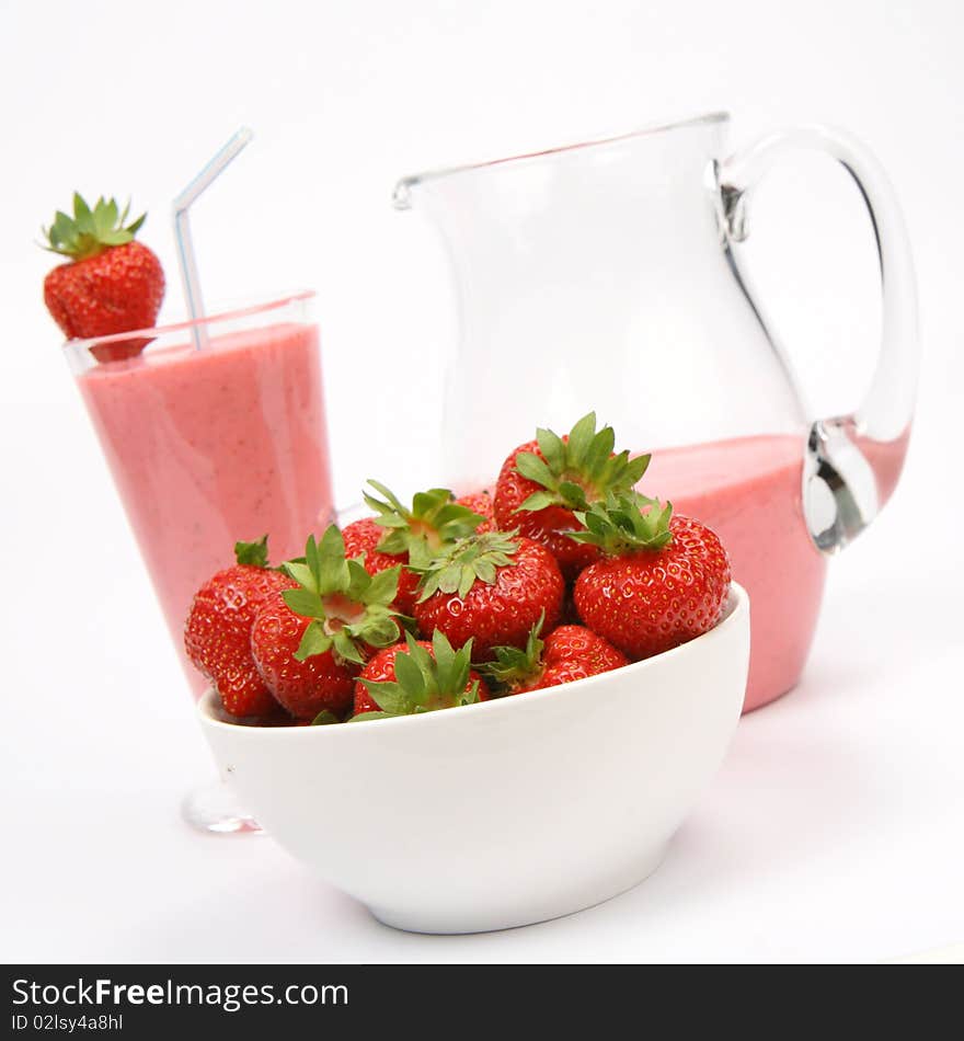 Strawberries in a bowl and a strawberry shake in a glass with a straw and in a jug on white background. Strawberries in a bowl and a strawberry shake in a glass with a straw and in a jug on white background