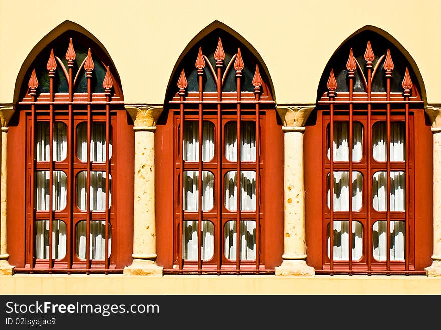 Three red windows ona still wall with archs. Three red windows ona still wall with archs