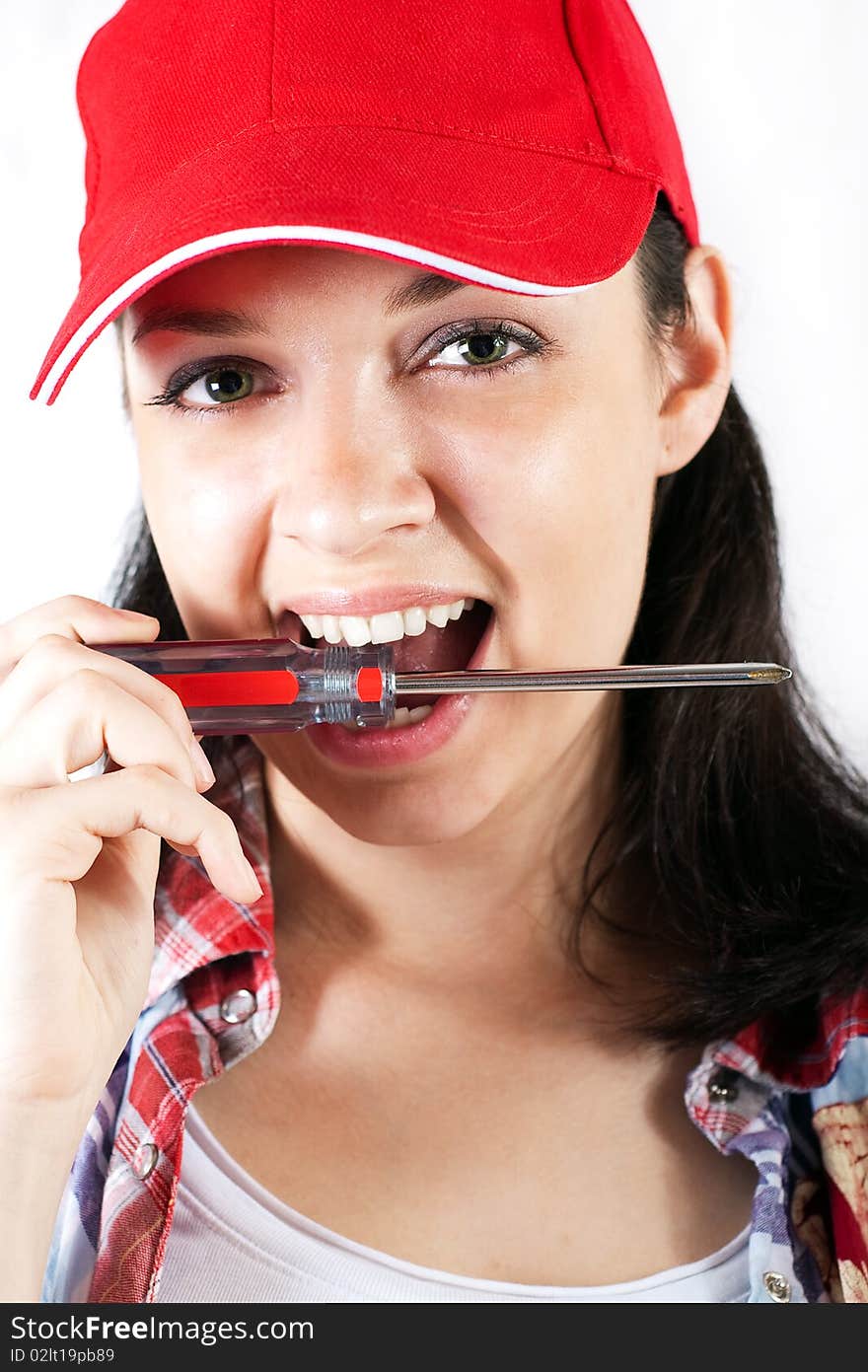 Carpenter girl holding a screwdriver in her mouth