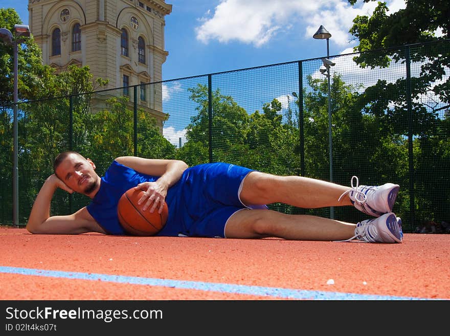 Basketball player with basketball ball relaxes on the sportground. Basketball player with basketball ball relaxes on the sportground