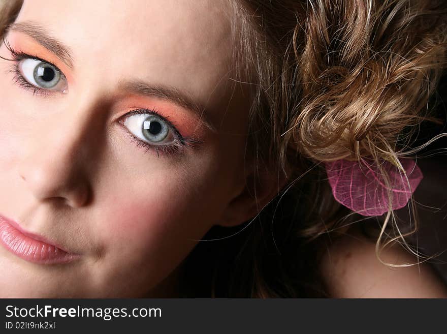 Close up of a beautiful blond with blue eyes and flower in her hair