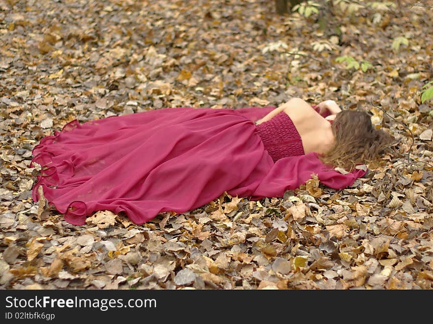 A girl in a red dress lying on the fallen leaves. A girl in a red dress lying on the fallen leaves