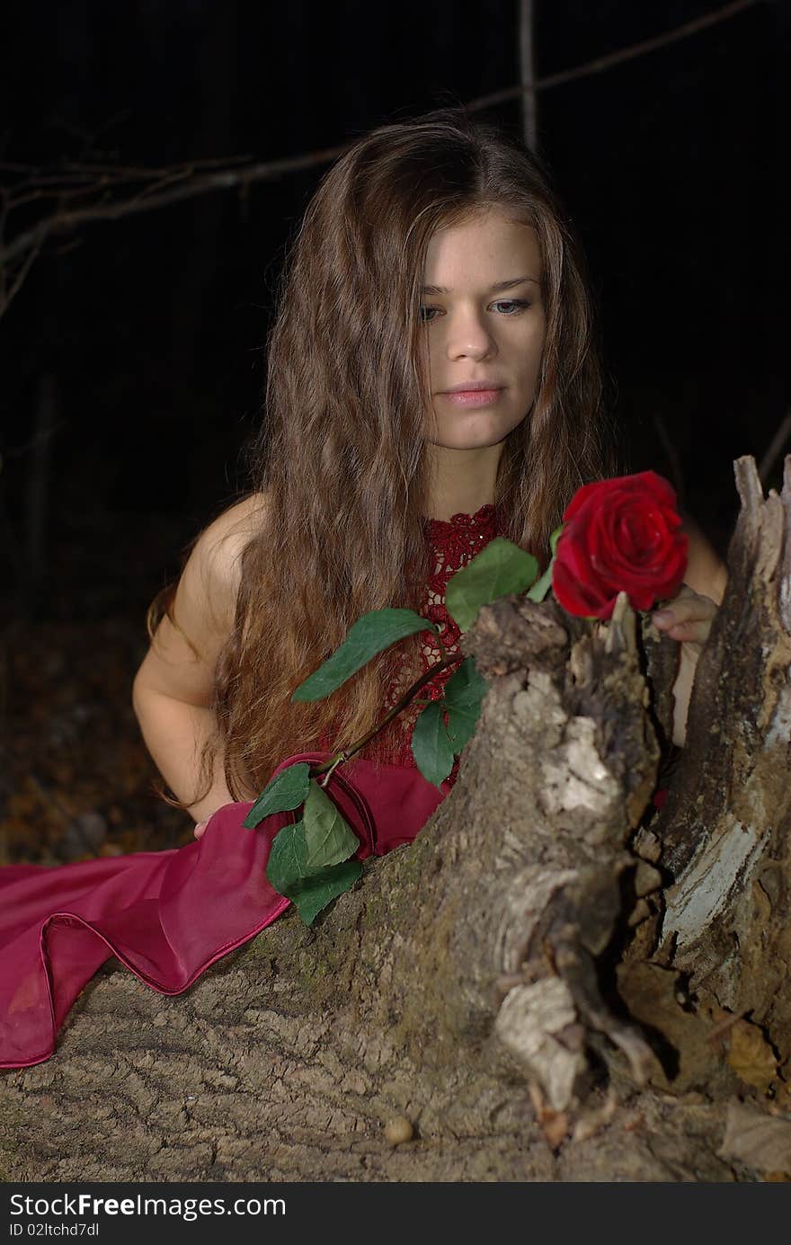 Girl in red dress on a stump with a red rose. Girl in red dress on a stump with a red rose