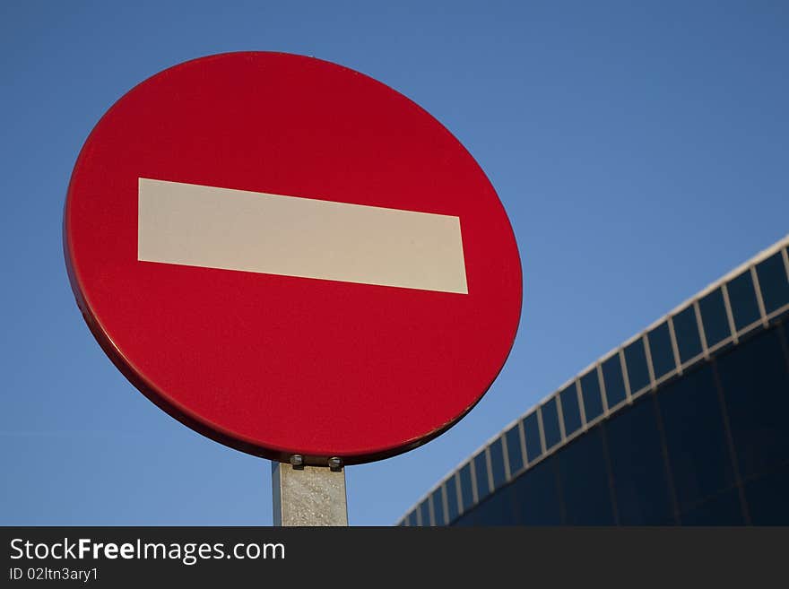 Red no entry sign with modern office detail in the background