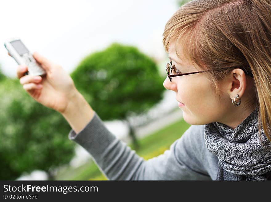 The girl holds a mobile phone in hands