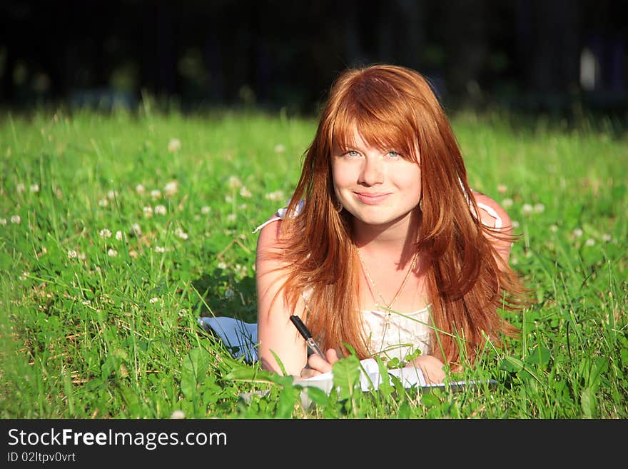 The girl smiles, in the grass at summer. The girl smiles, in the grass at summer