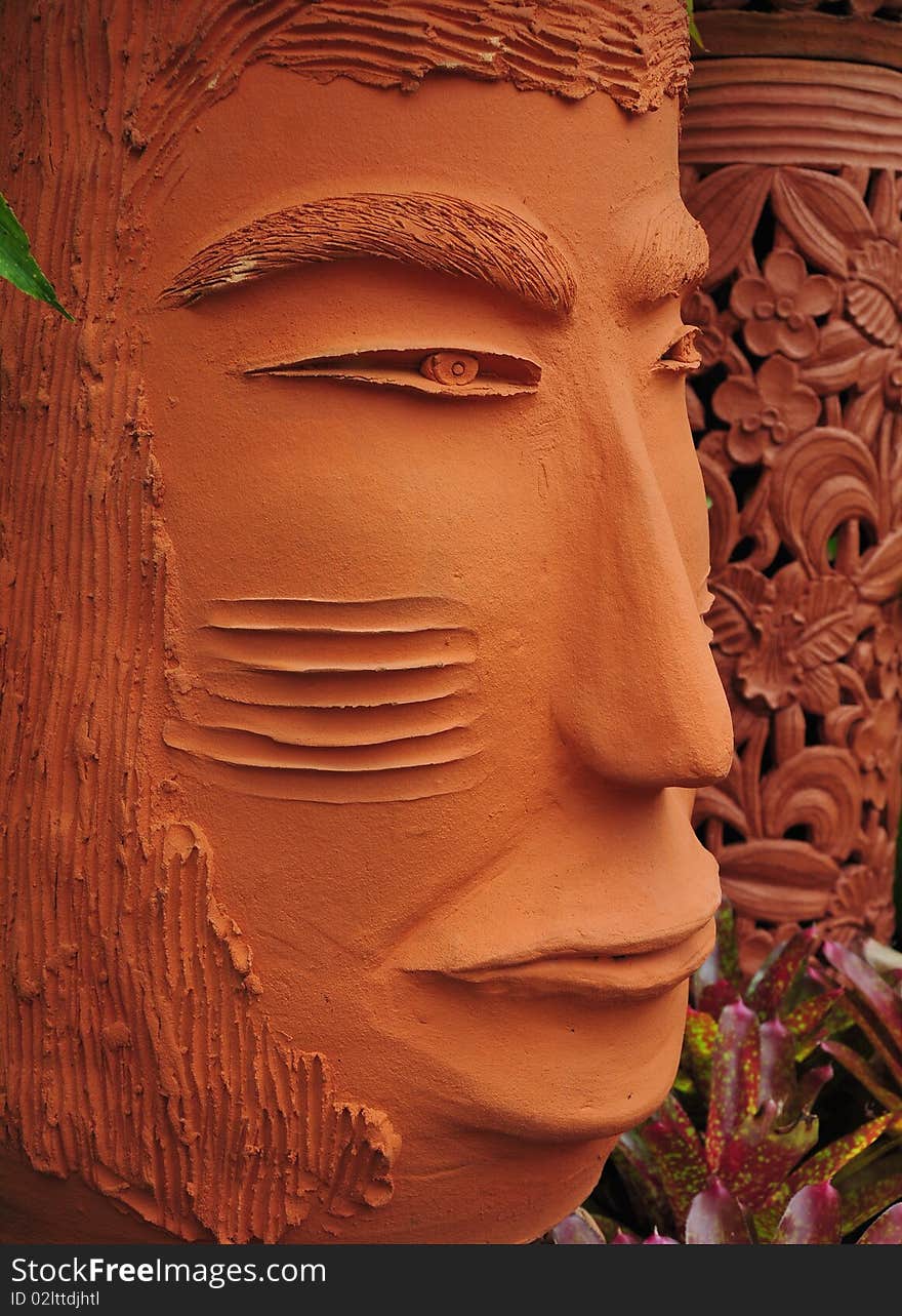 Strict looking orange colored terracotta face