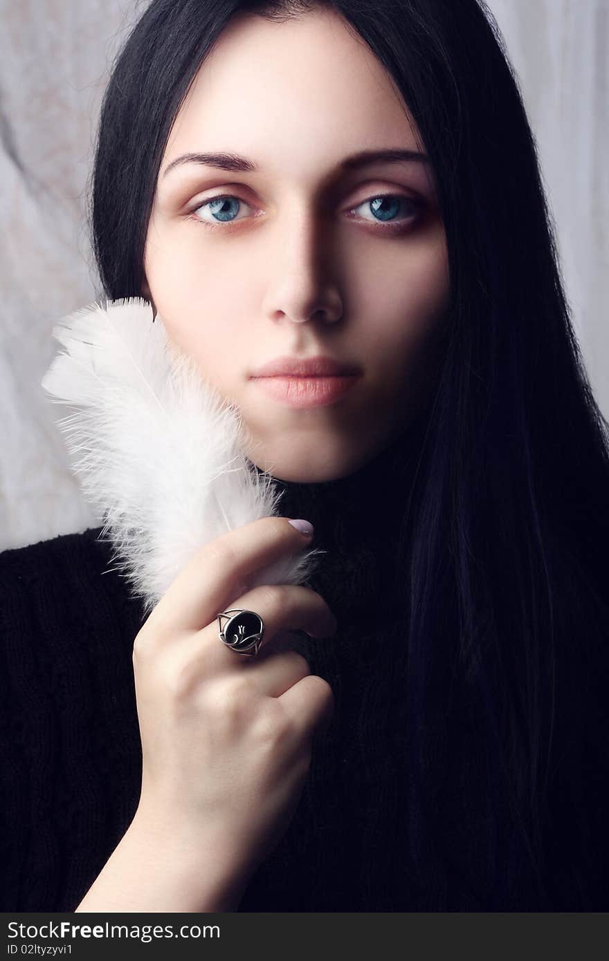 Portrait of the young girl with the beautiful blue eyes, a holding a bird feather in a hand