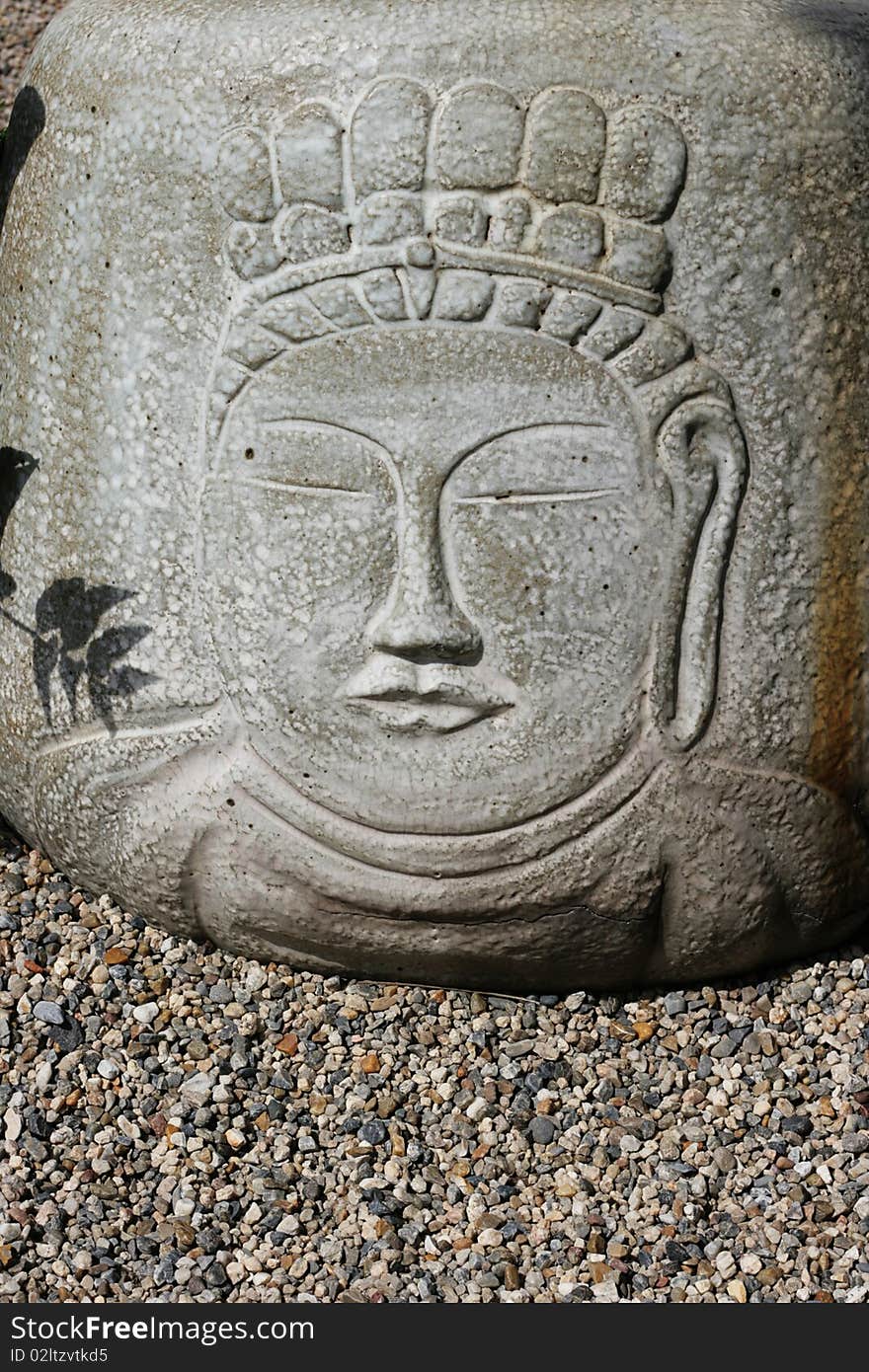 Buddha's face has been carved onto stone. It's simple in design, Zen style and is placed in a Japanse styled garden. Buddha's face has been carved onto stone. It's simple in design, Zen style and is placed in a Japanse styled garden.