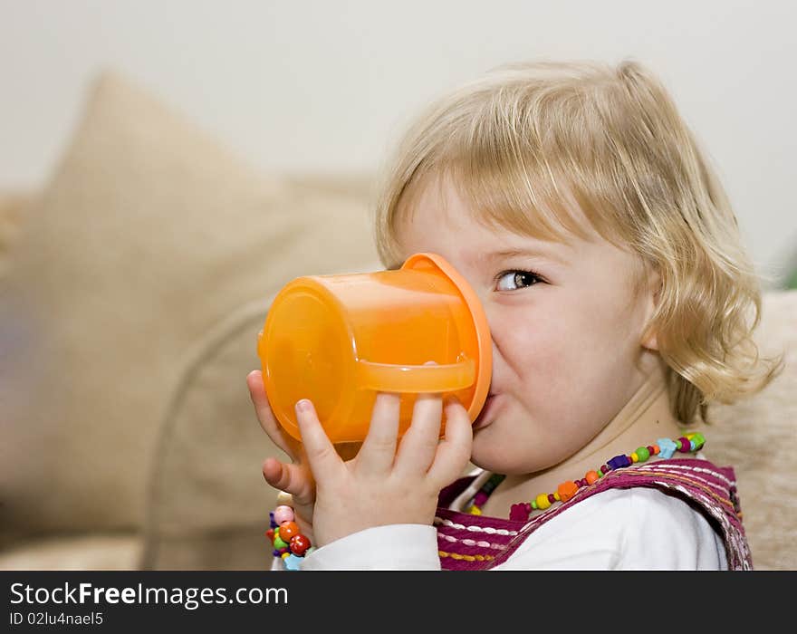 An adorable cute little girl drinking from a training cup. An adorable cute little girl drinking from a training cup