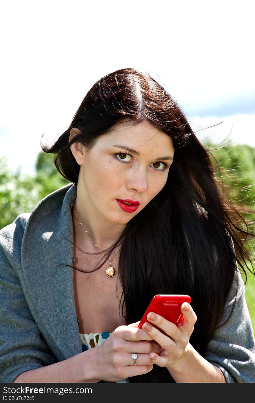 Young cute women with mobile phone in the green park background