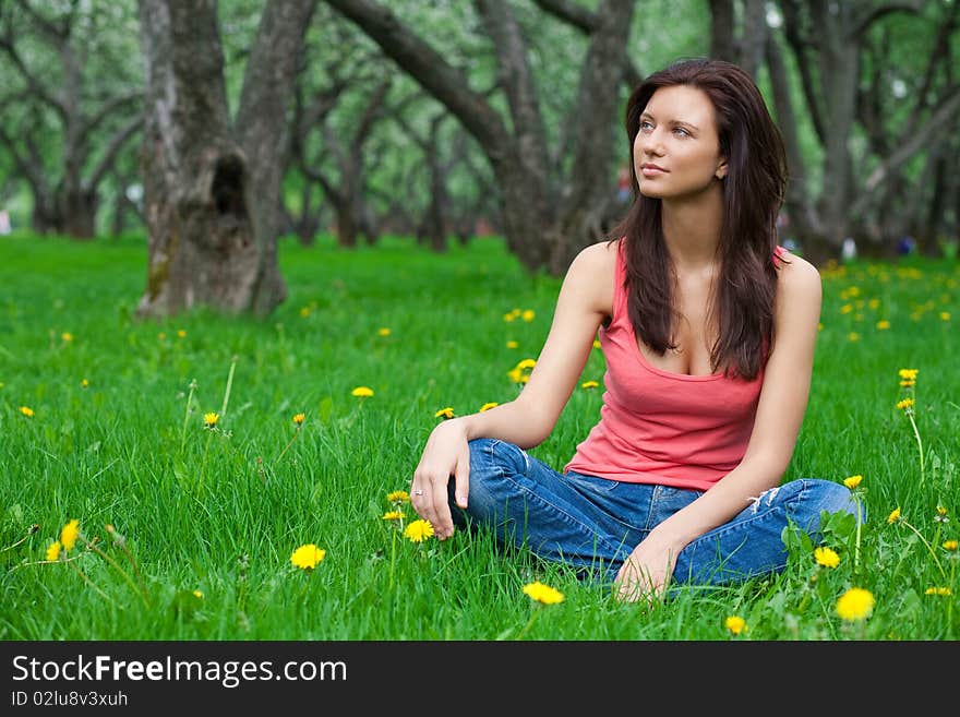 Beautiful brunette girl sitting on grass