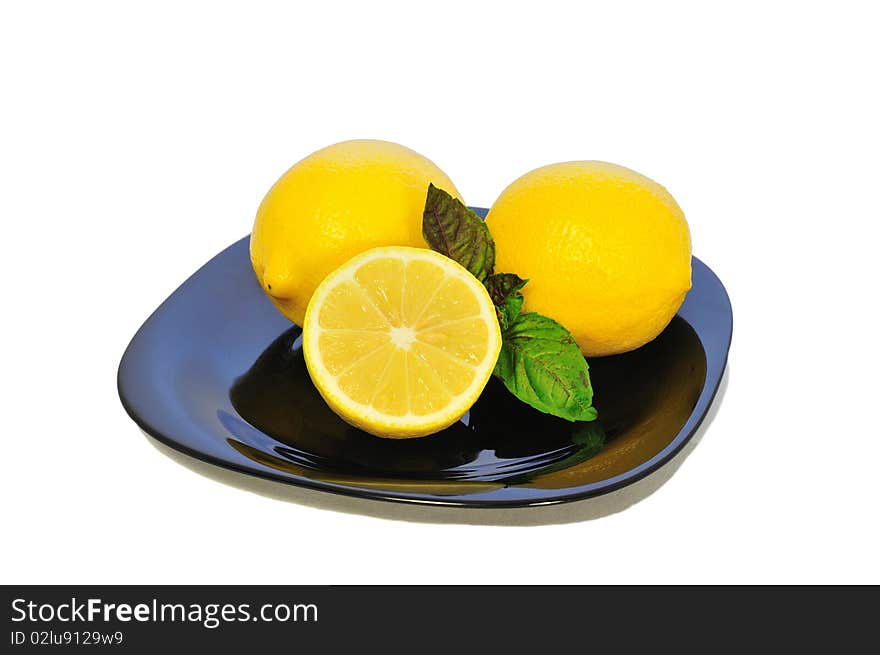 Isolated Yellow lemons on the black plate. Isolated Yellow lemons on the black plate