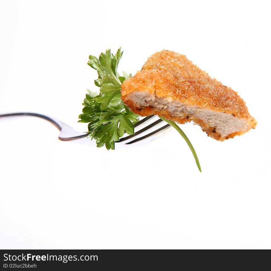 Piece of pork chop (covered in batter and breadcrumbs) with parsley on a fork on white background. Piece of pork chop (covered in batter and breadcrumbs) with parsley on a fork on white background