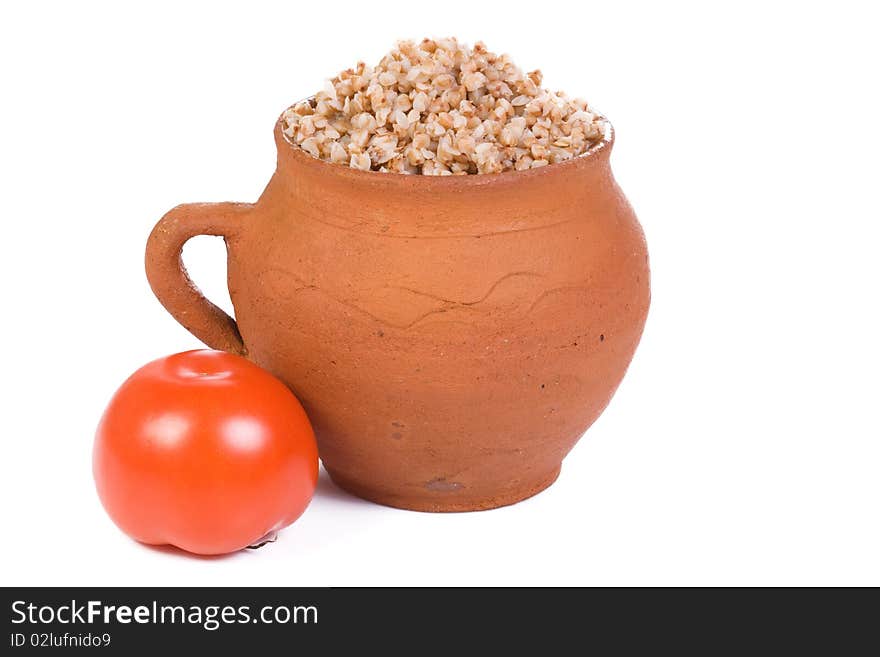 Tomato and ceramic pot with buckwheat porridge