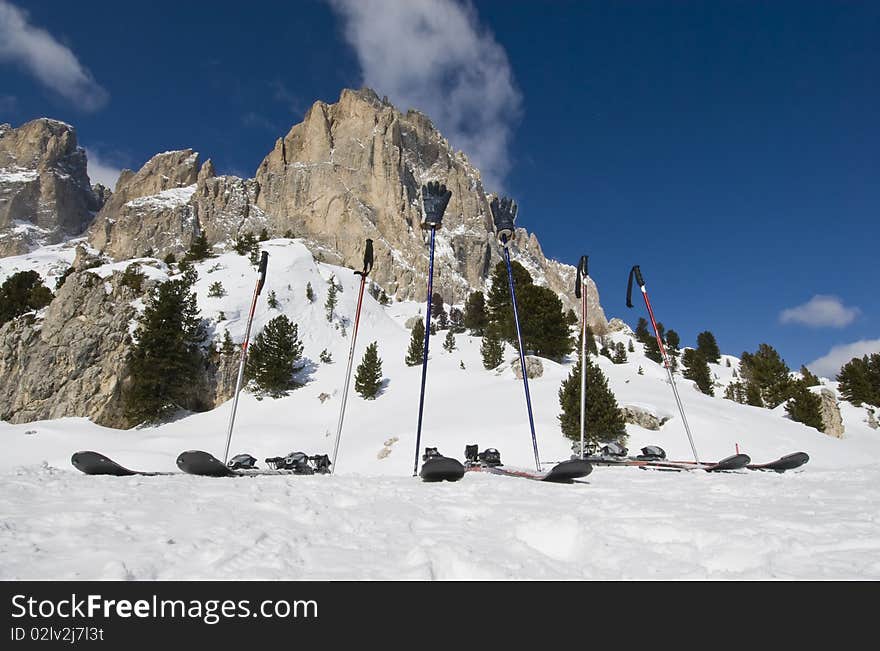 Three pairs of skies and poles on the snow in front of a mountain with no people. Val Gardena, Dolomites, Italy. Three pairs of skies and poles on the snow in front of a mountain with no people. Val Gardena, Dolomites, Italy.