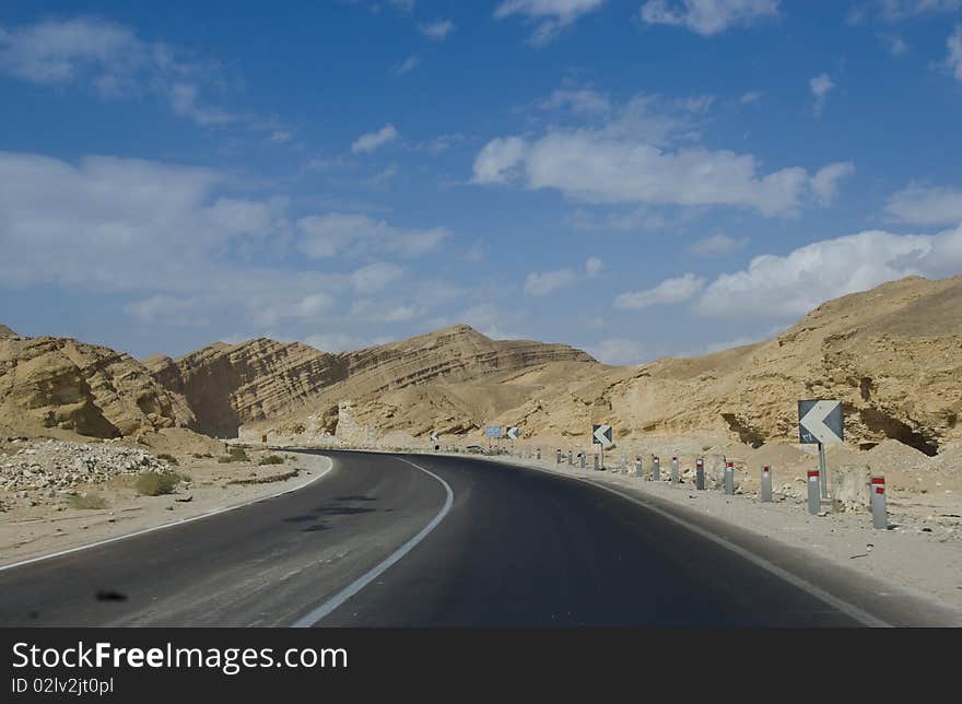 Desert road leading towards mounains.