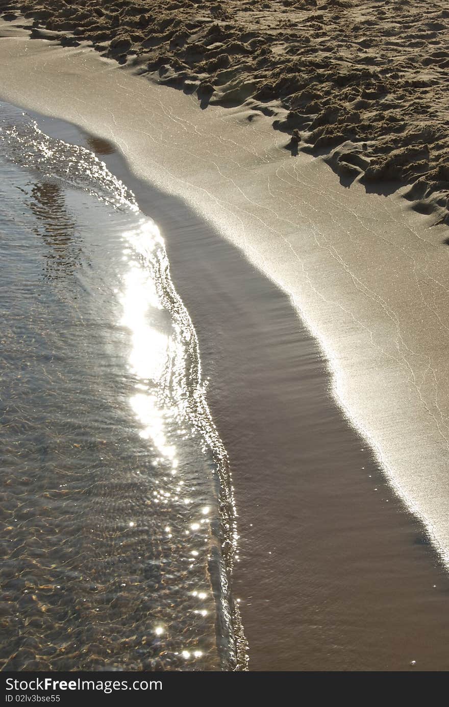 Gentle surf coming onto a sandy beach at sunset. Ras Mohamed National Park, South Sinai, Red Sea, Egypt. Gentle surf coming onto a sandy beach at sunset. Ras Mohamed National Park, South Sinai, Red Sea, Egypt.