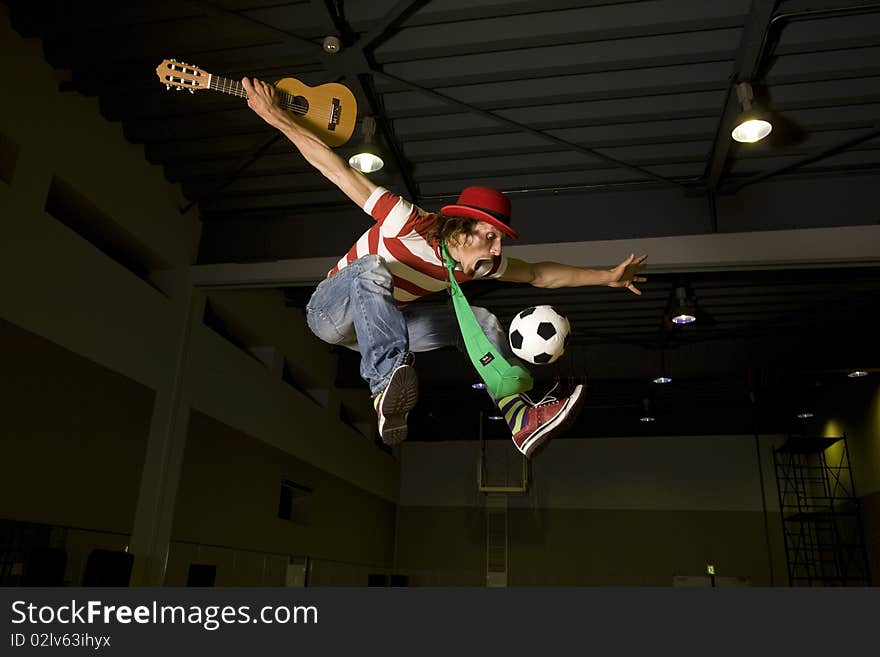 An entertainer flies high holding a guitar while playing soccer. An entertainer flies high holding a guitar while playing soccer