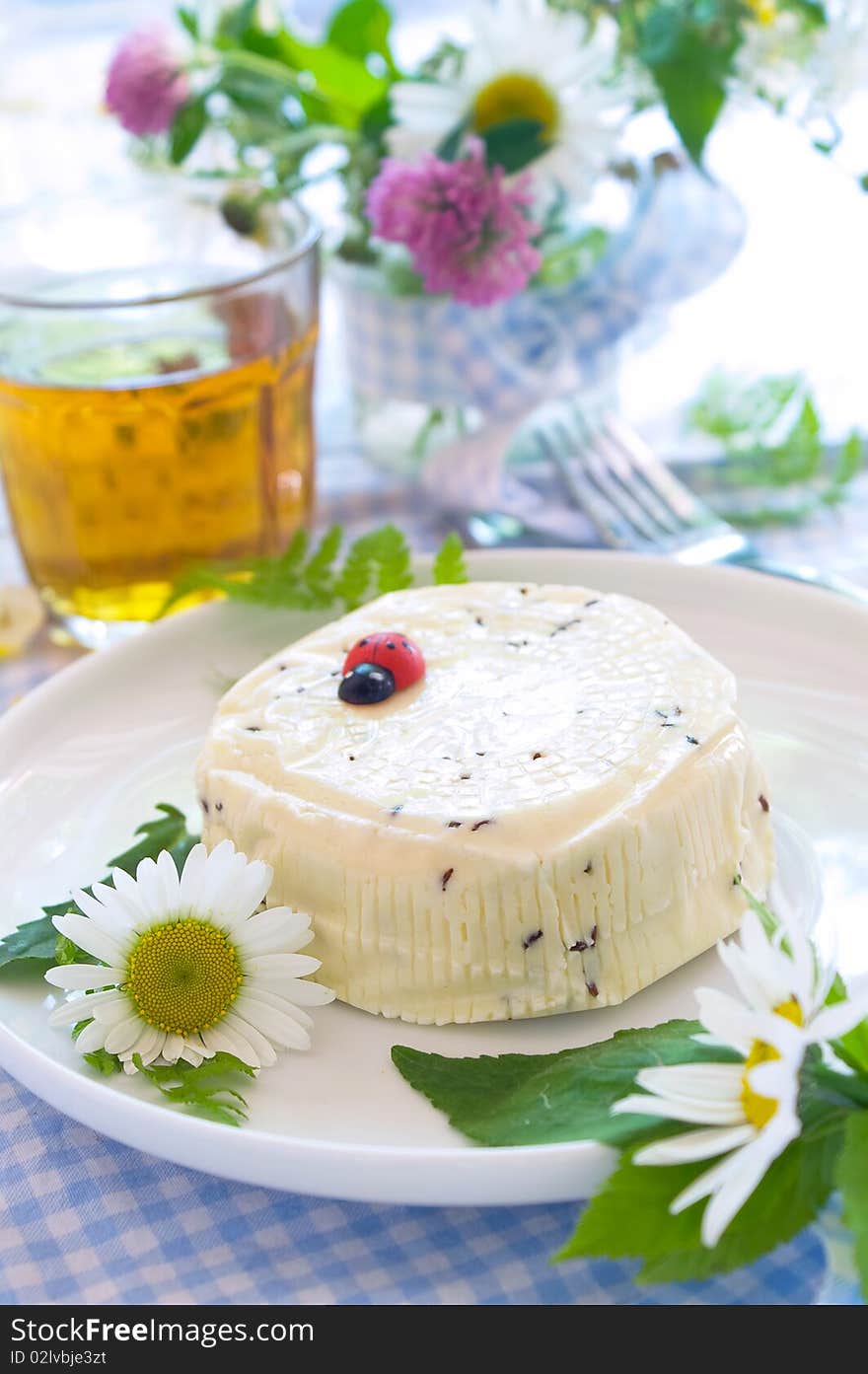 Traditional homemade cheese with caraway seeds on the plate. Dekorated with wild flower