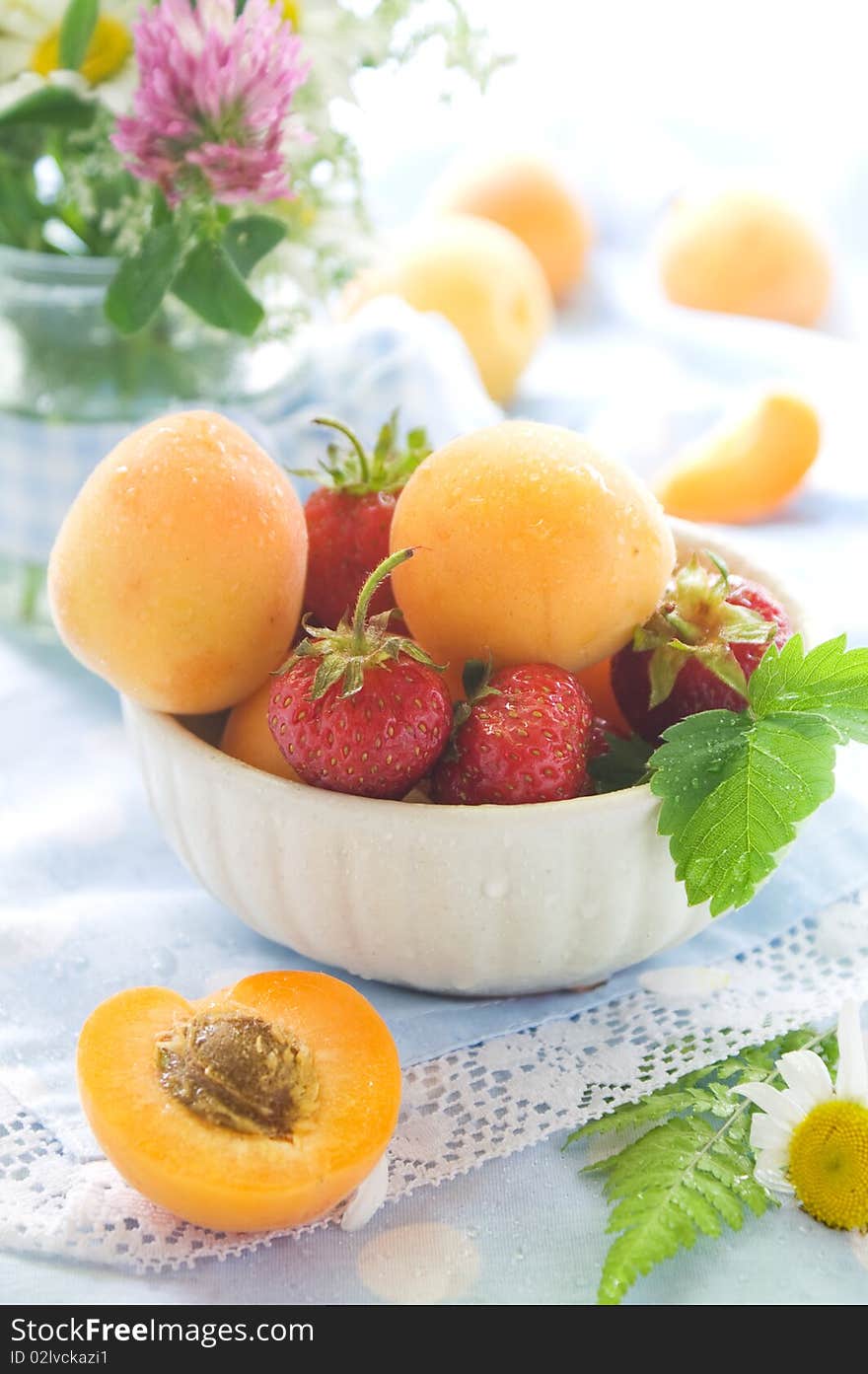 Fresh apricots and strawberries in and beside bowl