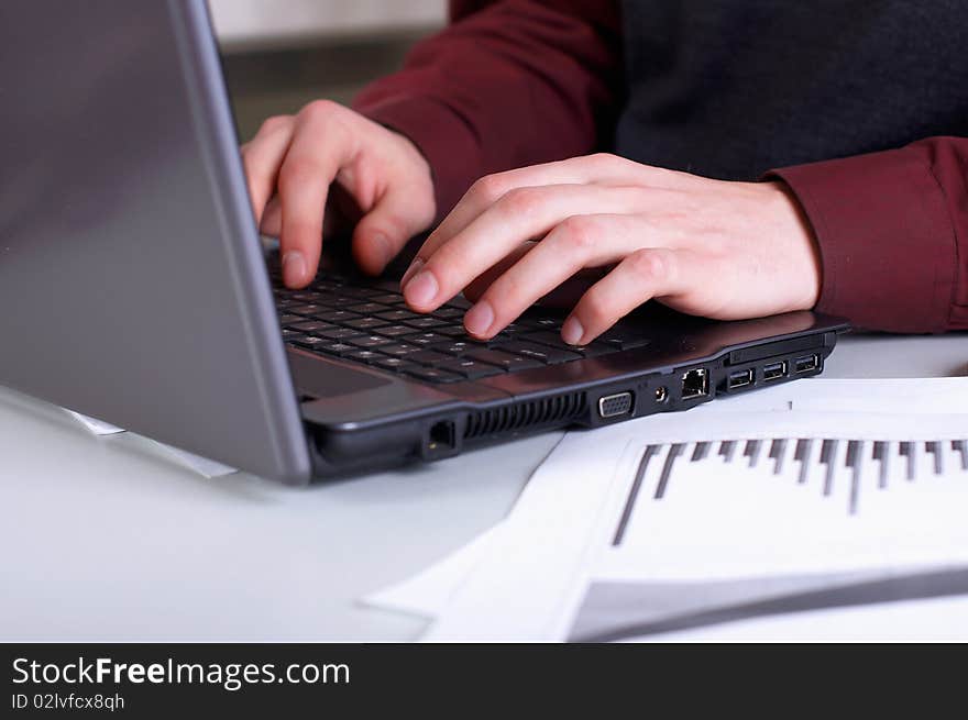 Hands of a young man working on laptop